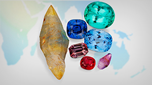 An array of rough and polished colored gemstones sitting on a world map.