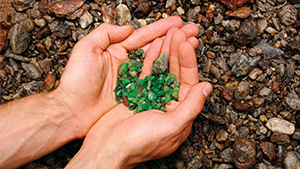 Hands holding rough tsavorite in the field