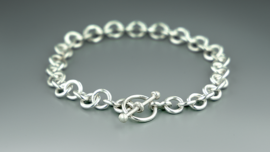 Create a handmade chain and toggle clasp in sterling silver. Learn skills like soldering, chain assembly, forming a wire loop, fusing metal with a torch, and making a toggle clasp.